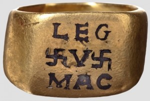 Χρυσό δαχτυλίδι αξιωματικού του 2ου με 3ου αιώνα, της 5ης (λατινικό γράμμα V) Λεγεώνας Μακεδονίας. Το LEG στο πάνω μέρος για το ΛΕΓεώνα και το MAC κάτω για το ΜΑΚεδονία. Αμφιπλεύρως του V, του αριθμού της Λεγεώνας δηλαδή (5), υπάρχουν σβάστικες, σύμβολο από την αρχαιότητα και στην ρωμαϊκή εποχή, διακοσμητικό αλλά πίστευαν ότι έφερε ισχύ και τύχη, ίσως ήταν ένας λόγος που το χρησιμοποίησε ως το βασικό του σύμβολο ο ναζιστής Χίτλερ, κακοχαρακτηρίζοντάς το.